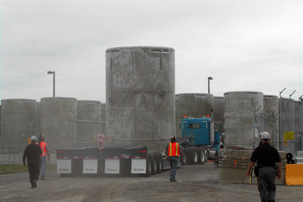 A vertical concrete container (storage cask) being hauled by semi truck into the ISFSI